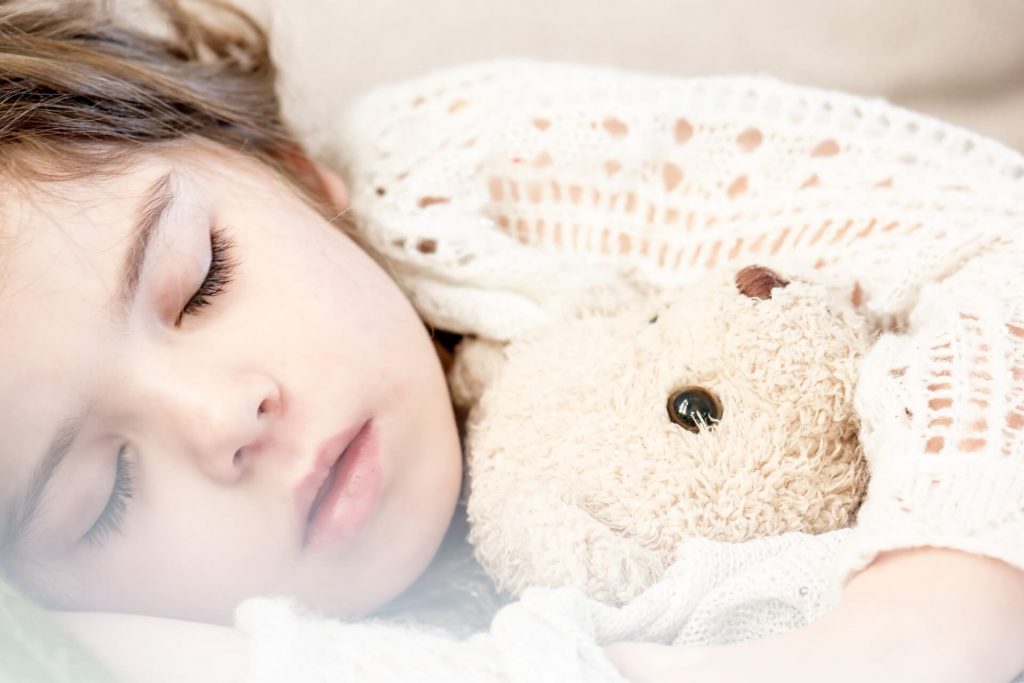 a sleeping child hugging a soft toy